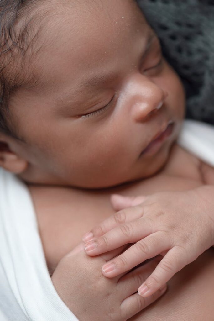A close-up of a peaceful newborn baby sleeping wrapped in a soft blanket.